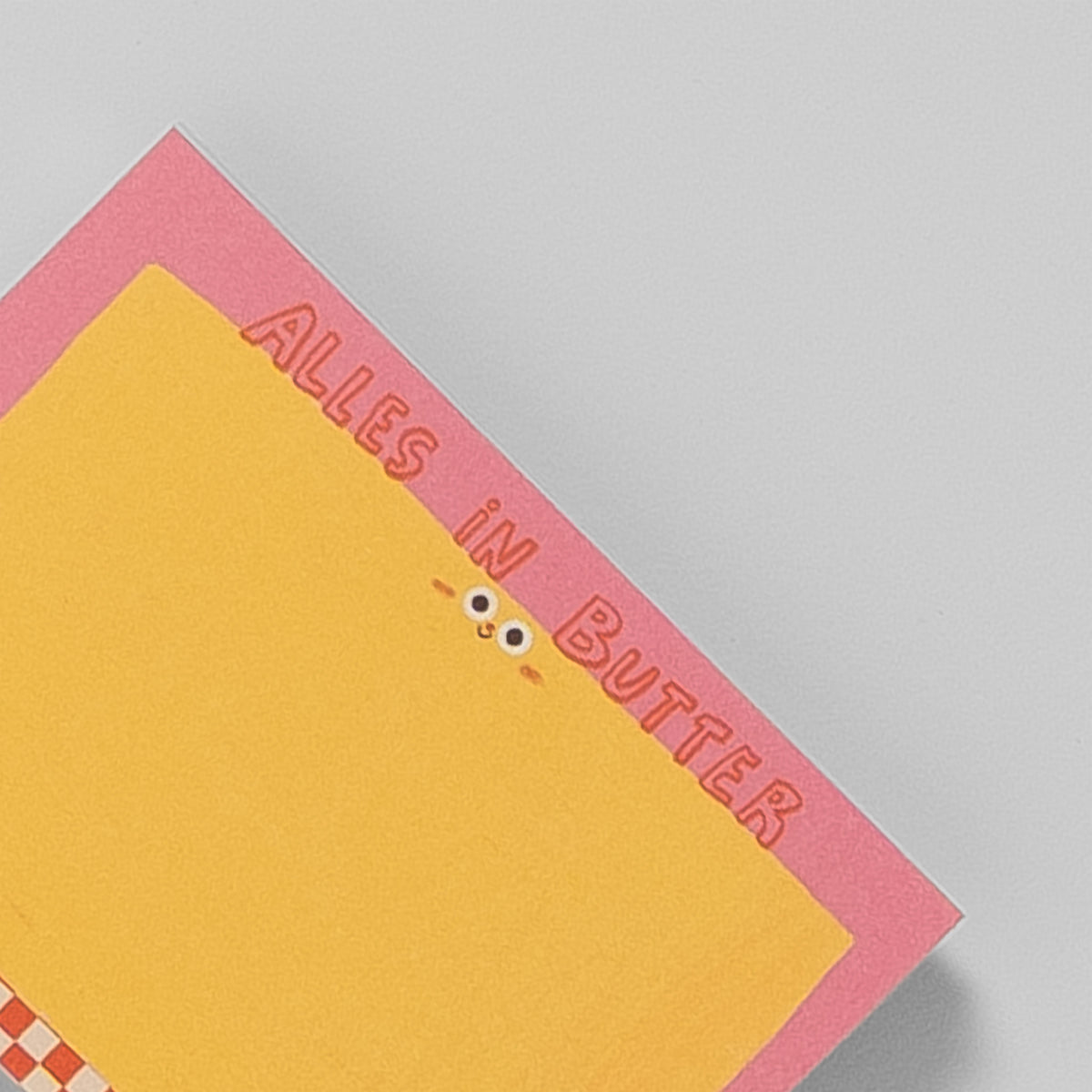 Notizblock A7 „Alles in Butter“ von Slinga, Nahaufnahme des Schriftzugs und der Kulleraugen-Butter